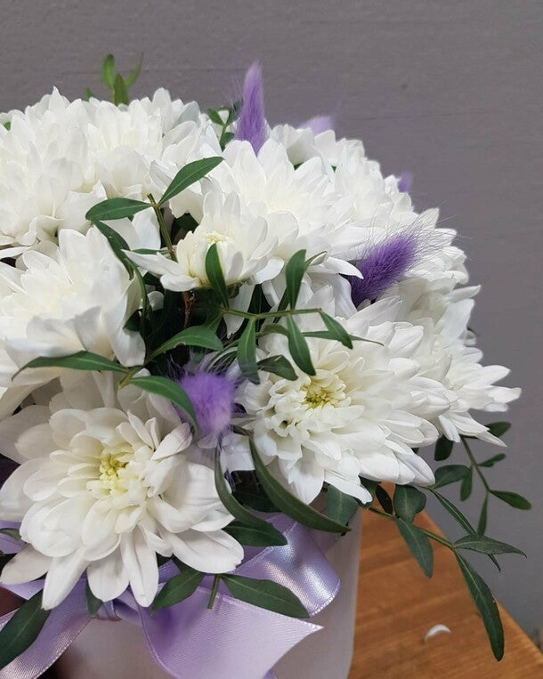 A box with a white bush chrysanthemum and a "present" lagurus