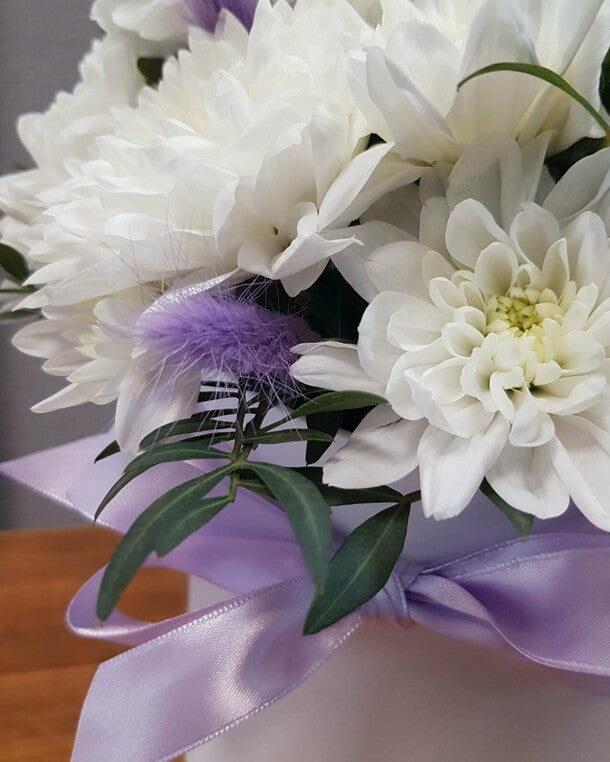 A box with a white bush chrysanthemum and a "present" lagurus